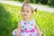 Cute little girl wearing polka dots dress sitting on the grass o