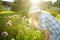 Cute little girl wearing straw hat admiring tall purple garlic flowers on sunny summer day. Child and flowers, summer, nature and