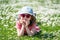 A cute little girl wearing sunglasses enjoys lying on the grass amongst daisies in a meadow