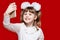 A cute little girl in white bows hold telephone and take picture