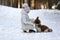 Cute little girl in a white coat with a dog walk in the winter forest. A child is training a dog. Obedience training. Children and