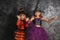 Cute little girls dressed as witches for Halloween near dark wall