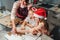 Cute little girls in red Santa hats with mother making homemade dough Christmas gingerbread cookies using cookie cutters together