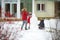 Cute little girls and their grandma building a snowman in the backyard. Cute children playing in a snow.