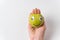 Cute little green Apple with Googly eyes lying on palm. White background