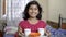 Cute Little happy Indian Asian Caucasian girl child holding tea cups and snacks in a tray front view portrait.