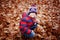 Cute little kid boy on autumn leaves background in park.