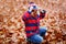 Cute little kid boy on autumn leaves background in park.