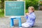 Cute little kid boy with glasses at blackboard practicing writin