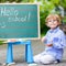 Cute little kid boy with glasses at blackboard practicing writin