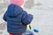 Cute little kid boy in warm autumnal clothes turned from behind having fun with tricycle