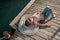 Cute little kid sunbathing lying on rope and wooden pier