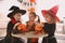 Cute little kids with candy buckets wearing Halloween costumes at home