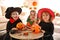 Cute little kids with candy buckets wearing Halloween costumes at home