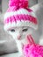 A cute little kitten in a pink knitted hat with pompoms looks on something frown. Cute little kitty in hat on a white