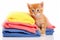 Cute little kitten with stack of colorful towels isolated on white background, Cute ginger kitten on pile of colorful towels,