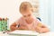 Cute little left-handed girl drawing at table