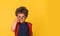 Cute little nerd smart boy wearing glasses isolated on yellow background. Funny pupil with red big backpack ready to go