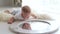 A cute little newborn baby is playing with a mirror at home lying on the bed.
