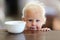 Cute Little One Year Old Baby Girl Next to Cereal Bowl in Kitchen