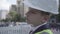 Cute little pensive boy wearing business suit and safety equipment and constructor helmet standing on a busy road in a