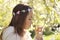 Cute little pensive girl with handmade hair wreath on her head smelling flowers in the spring blossom garden