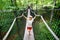 Cute little preschool girl walking on high tree-canopy trail with wooden walkway and ropeways on Hoherodskopf in Germany