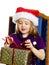 Cute little preschooler girl in red santa hat with gift box