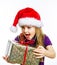 Cute little preschooler girl in red santa hat with gift box