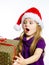 Cute little preschooler girl in red santa hat with gift box