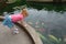 Cute little redhaired girl looking at goldfish pond