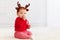 cute little redhead baby boy with reindeer band tasting christmas sweet treats, sitting on the floor at home