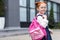 cute little redhead schoolgirl in eyeglasses holding backpack and smiling