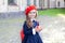 Cute little schoolgirl in red beret and school uniform holds apple in her hands. School break. Fruit snack. Vegetarian child. Diet