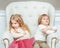 Cute little siblings (boy and girl) being at odds with each other, sitting on armchair