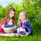 Cute little sisters picking fresh berries on organic blueberry farm