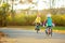 Cute little sisters riding bikes in a city park on sunny autumn day. Active family leisure with kids