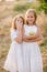 Cute little sisters in white dresses laugh laughing with apples and pears in the countryside on a autumn day