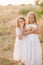 Cute little sisters in white dresses laugh laughing with apples and pears in the countryside on a autumn day