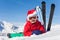 Cute little skier in Santa`s hat laying on snow