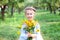 Cute little smiling girl in with a bouquet of yellow flowers in garden. Cheerful child with daisies. Portrait little girl with bou