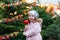 Cute little smiling preschool girl on German Christmas market. Happy child in winter clothes eating sweet sugared glazed