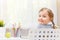 A cute little student girl is sitting at the table with her back. The child turned around and looks into the camera.