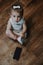 Cute little toddler baby girl with cell phone near on the floor. Vertical portrait of kid sitting on floor with mobile