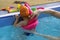 Cute little toddler boy child kicking feet in swimming costume use pool noodle and kickboard learn to swim at indoor
