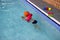 Cute little toddler boy child kicking feet in swimming costume use pool noodle and kickboard learn to swim at indoor