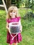 Cute little toddler girl holding bucket with ripe sweet red cherries. Happy child picking fresh organic berries in