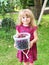 Cute little toddler girl holding bucket with ripe sweet red cherries. Happy child picking fresh organic berries in