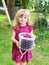 Cute little toddler girl holding bucket with ripe sweet red cherries. Happy child picking fresh organic berries in