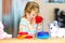 Cute little toddler girl playing alone with colorful wooden rainbow pyramid and toys at home or nursery. Happy healthy